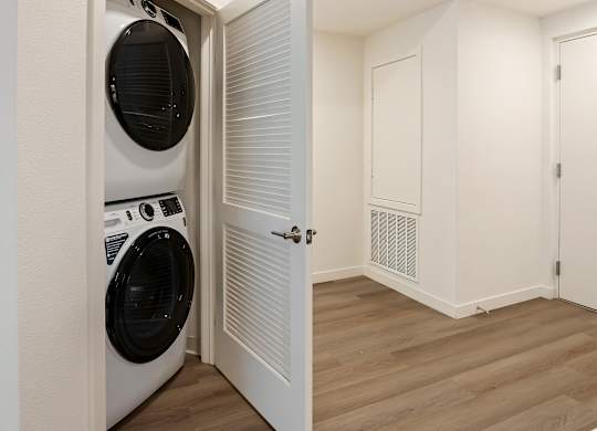 Stacked washer and dryer with louvered closet door at Elements Apartments, California