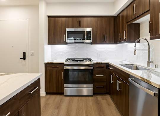 Contemporary kitchen with stainless range and white marble backsplash at Elements Apartments, Irvine, California