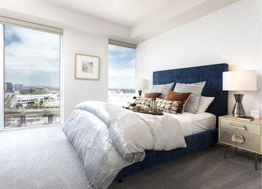 Bright bedroom with navy upholstered bed and city views at LUX by Garden* Apartments, California, 92122