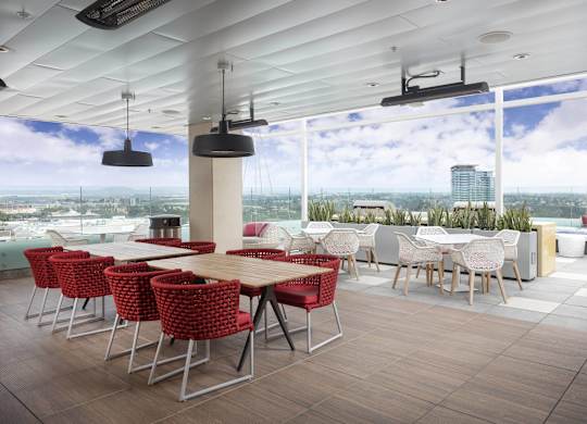 Rooftop patio with dining tables and skyline views at LUX by Garden* Apartments, San Diego