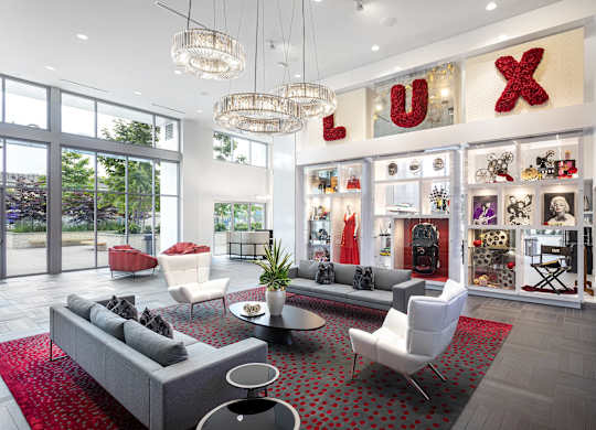 Elegant lobby with designer chandeliers and showcase wall at LUX by Garden* Apartments, California