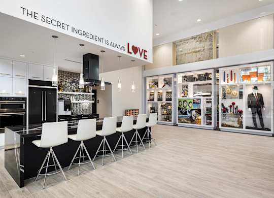 Community kitchen with island seating and wall display at LUX by Garden* Apartments, San Diego, CA 92122