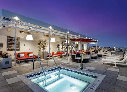 Rooftop hot tub with lounge furniture at dusk at LUX by Garden* Apartments, San Diego, 92122