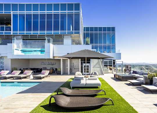 Rooftop pool deck with artificial turf and modern loungers at LUX by Garden* Apartments, California