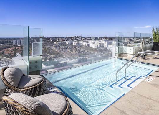 Rooftop spa with glass railing and city views at LUX by Garden* Apartments, California