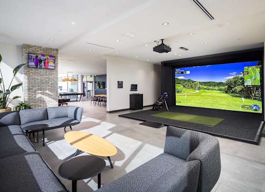 Indoor golf simulator lounge with putting green at LUX by Garden* Apartments, San Diego, CA