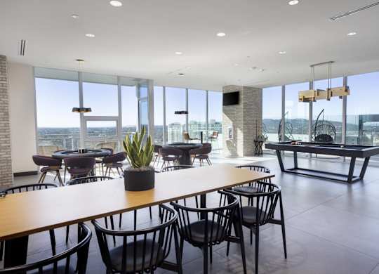 Community lounge with panoramic windows and dining tables at LUX by Garden* Apartments, San Diego