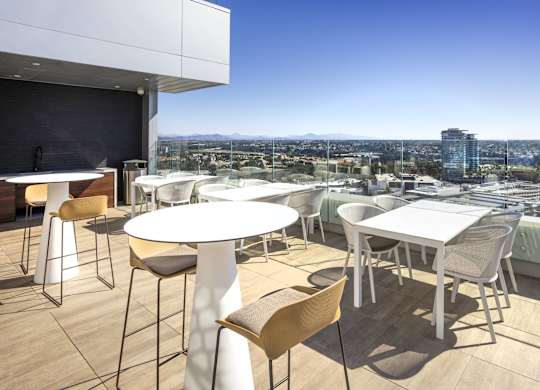 Rooftop dining area with bar seating and panoramic views at LUX by Garden* Apartments, California, 92122