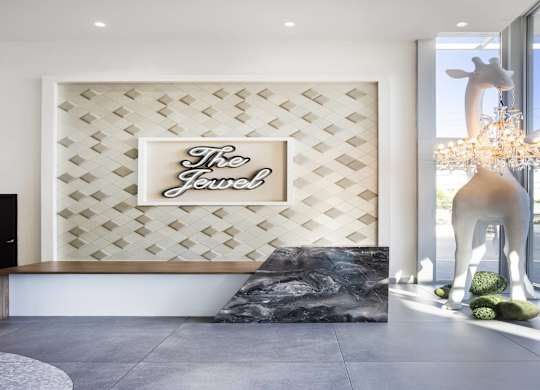 Reception desk with decorative wall and giraffe sculpture at LUX by Garden* Apartments, San Diego, CA 92122