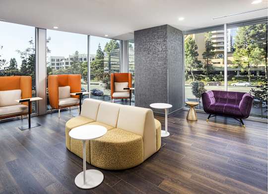 Modern lounge with orange privacy chairs and curved sofa at LUX by Garden* Apartments, San Diego