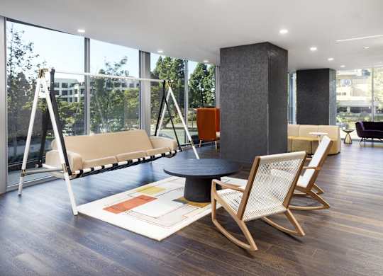 Lounge area with swing seating and floor to ceiling windows at LUX by Garden* Apartments, California
