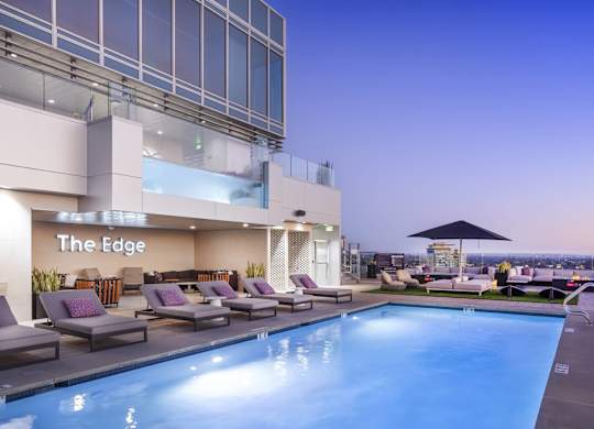Rooftop pool deck at twilight with loungers and umbrellas at LUX by Garden* Apartments, San Diego, California