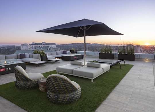 Rooftop lounge with umbrella seating and sunset views at LUX by Garden* Apartments, California