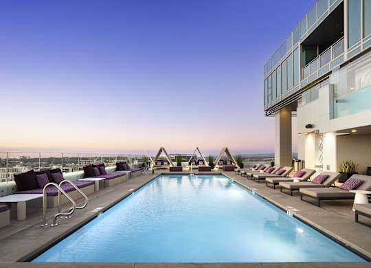 Rooftop pool with lounge chairs and cabanas at dusk at LUX by Garden* Apartments, San Diego, CA 92122