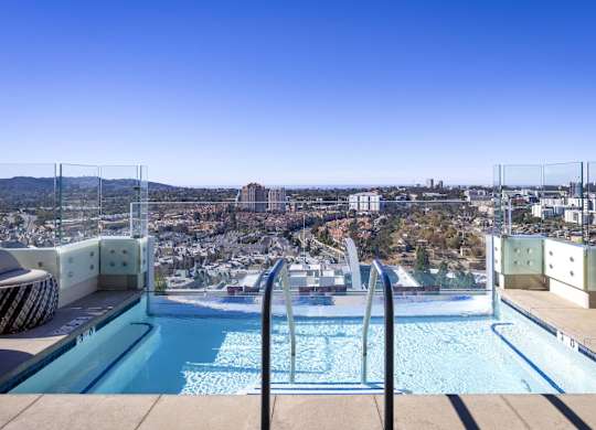 Rooftop infinity pool with glass railing and city skyline views at LUX by Garden* Apartments, San Diego, California