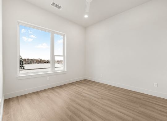 A room with a large window and wooden flooring.