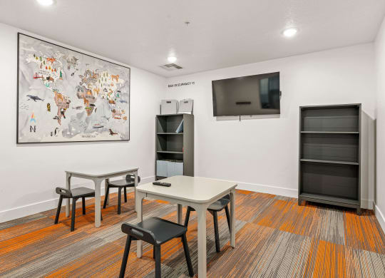 a room with a table and chairs and a television on the wall