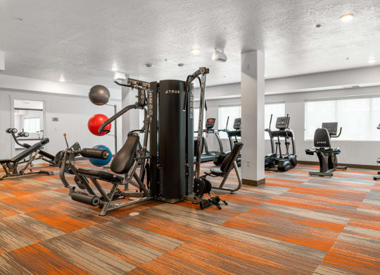 a large fitness room with cardio equipment and weights