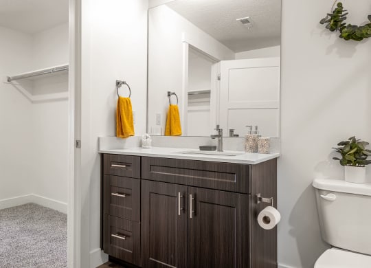 a bathroom with white walls and a dark wood vanity with a white countertop