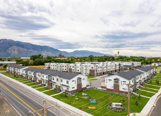 a row of apartment buildings with a street in the foreground and mountains in the background