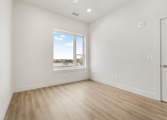 A room with a large window and wooden flooring.