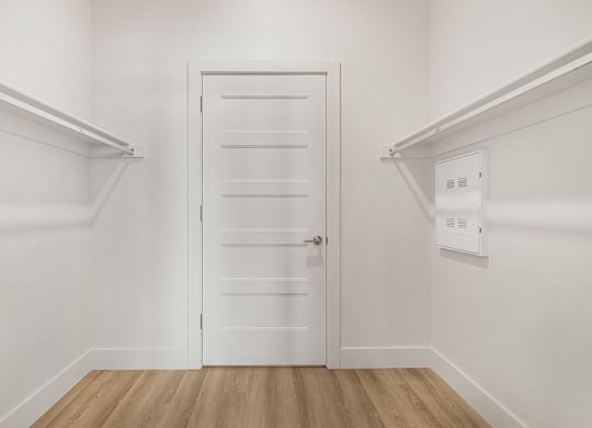 A white door with a handle is in the middle of a room with white walls.
