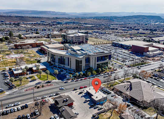 An aerial view of a parking lot with a red pin on a building.