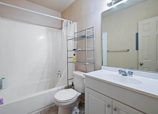 A white bathroom with a toilet, sink, and shower.
