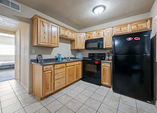 A kitchen with black appliances and wooden cabinets.