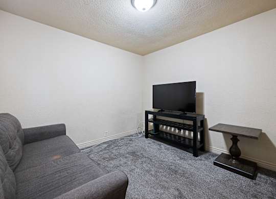 A grey sofa sits in a living room with a television and a small table.