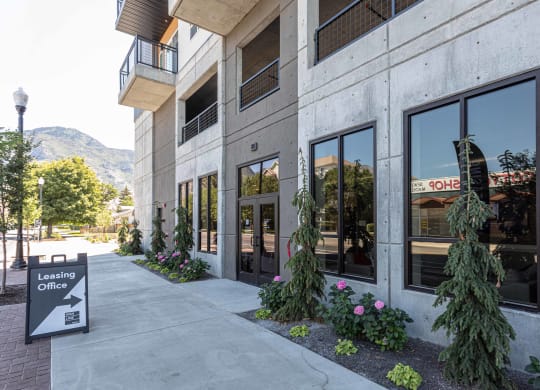 a building with a sidewalk and plants in front of it
