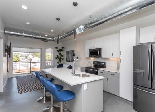 a kitchen with an island with blue chairs and a stainless steel refrigerator