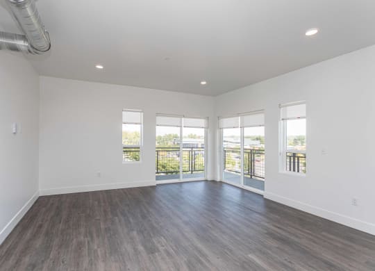 a living room with white walls and wood floors and a balcony