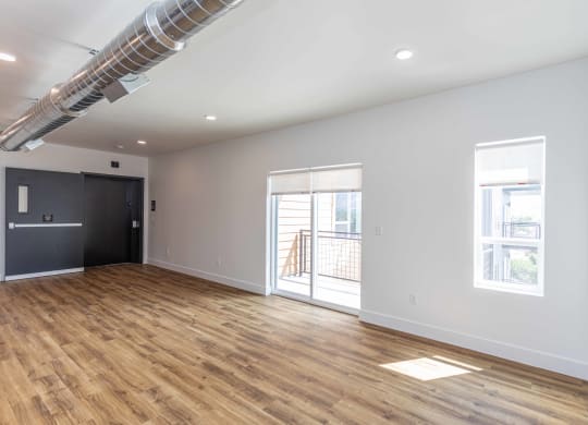 a living room with a hard wood floor and a door to a balcony