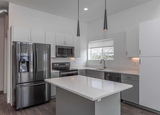 a white kitchen with stainless steel appliances and white counter tops