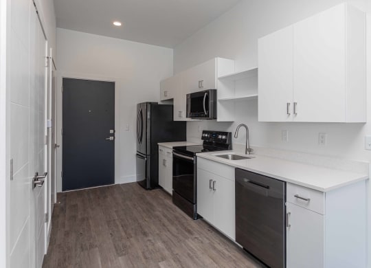 a kitchen with white cabinets and a black refrigerator