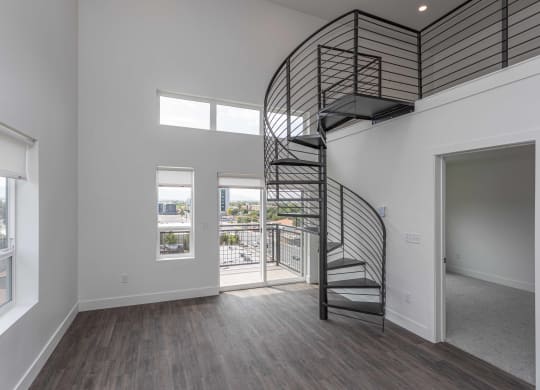 a spiral staircase in a living room with white walls and wood floors