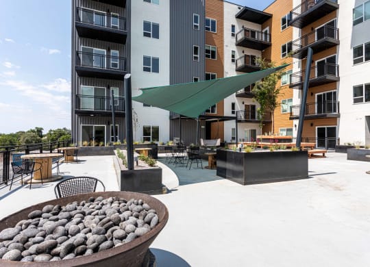 an outdoor patio with a fire pit and an apartment building