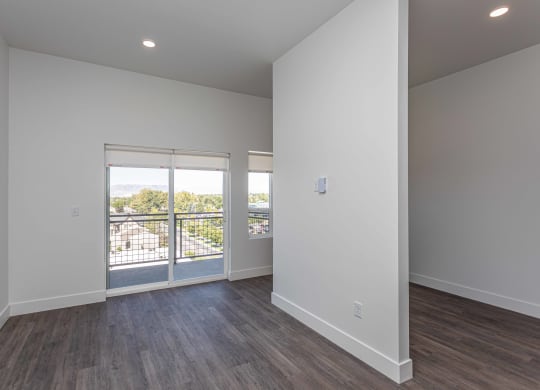 a living room with white walls and wood floors and a balcony
