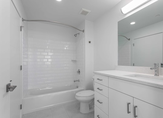 a white bathroom with a tub and a sink and a toilet