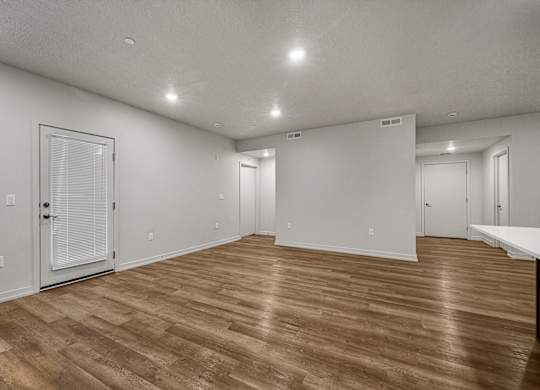 A room with wooden flooring and white walls.