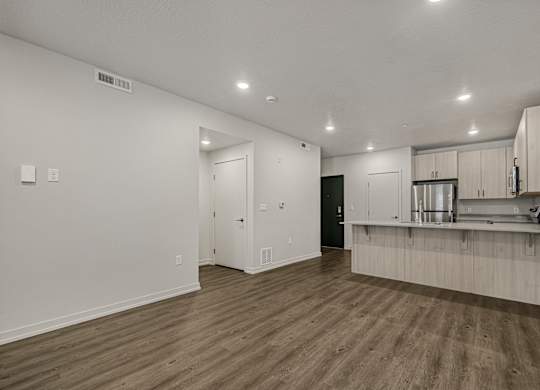 A kitchen with white cabinets and a wooden floor.