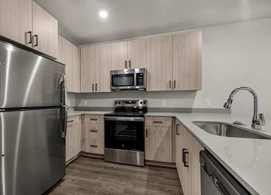 A modern kitchen with a stainless steel refrigerator and wooden cabinets.