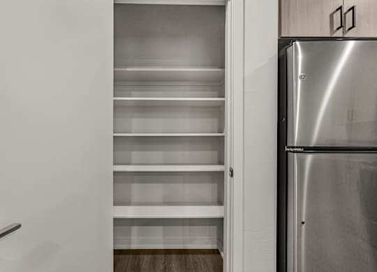 A kitchen with a refrigerator and empty shelves.