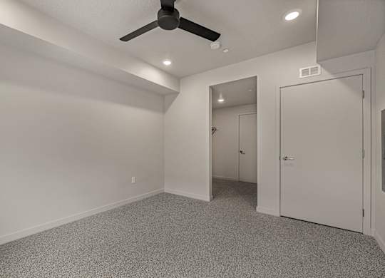 A room with a ceiling fan and carpeted floor.