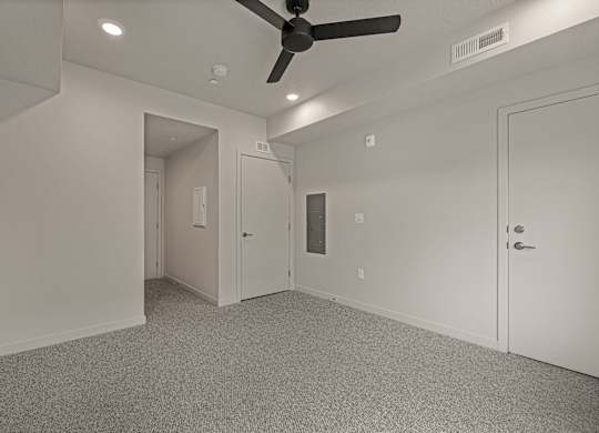 A room with a ceiling fan and carpeted floor.