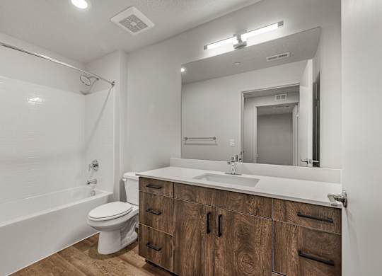 A modern bathroom with a wooden vanity and white fixtures.