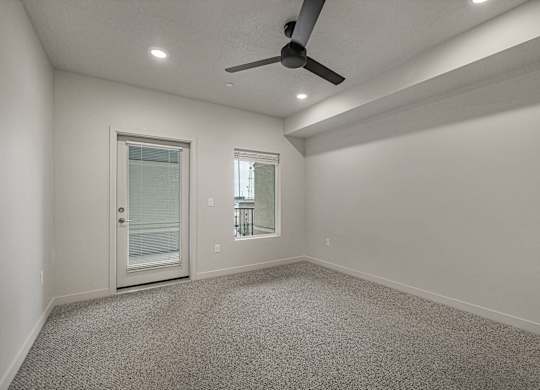 A room with a ceiling fan and two windows.