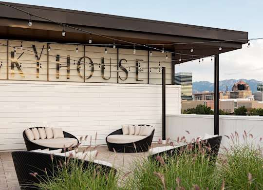 A patio area with a table and chairs in front of a building with the name "SKYHOUSE" on it.