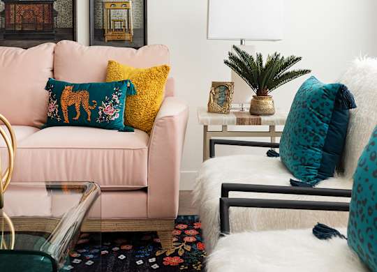 A living room with a pink couch and a white rug.